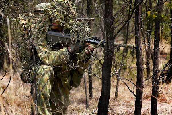 Scharfschütze in Tarnuniform mit Maschinengewehr im Wald