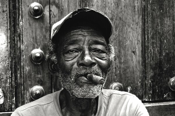 A man smoking in a cap, smoking a cigar