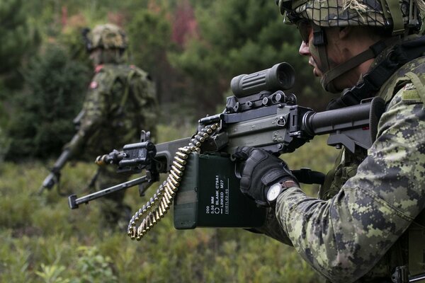 A soldier in uniform with a weapon in the forest