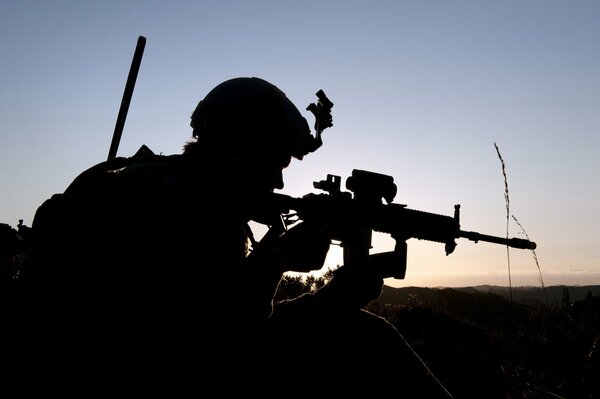 El crepúsculo de la noche y el rifle de asalto visible buscando el objetivo en la vista