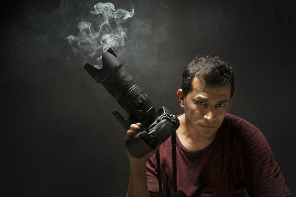 A smoking camera in the hands of a handsome man with a piercing gaze