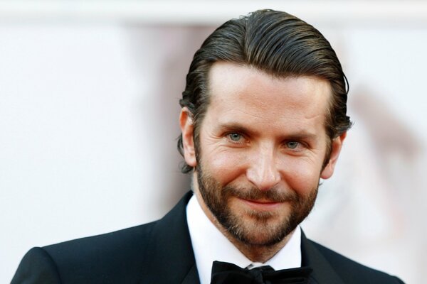 Schauspieler bradley cooper im Jackett und mit einem Schmetterling auf hellem Hintergrund