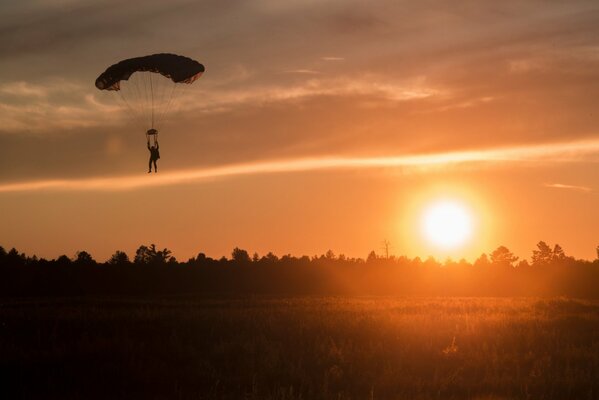 Silhouette d un parachutiste sur fond de soleil couchant