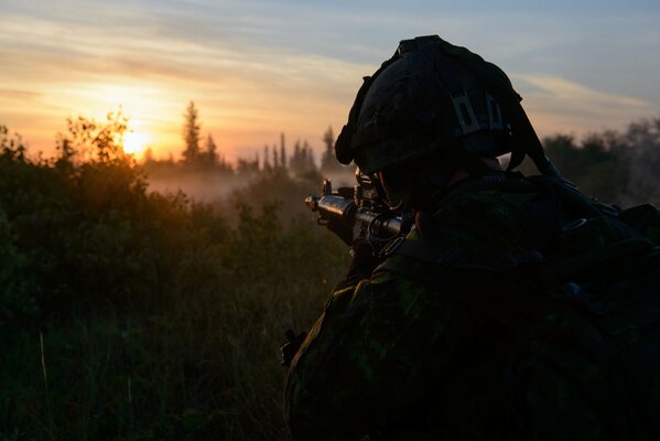 Soldado vigilando el objetivo en el fondo del amanecer