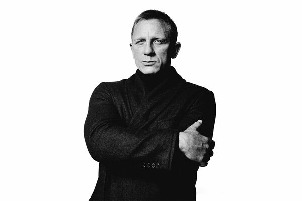 Schauspieler Daniel Craig im schwarzen Mantel auf weißem Hintergrund