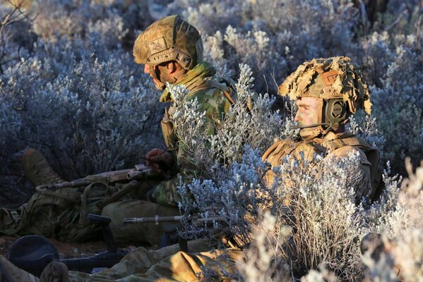 Soldati in uniforme giacciono tra le piante