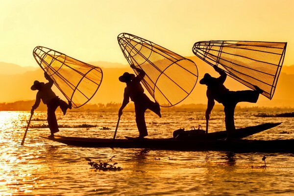 Silhouettes de pêcheurs sur la rivière au lever du soleil