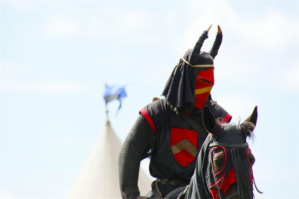 Guerrero con ropa negra y roja a caballo