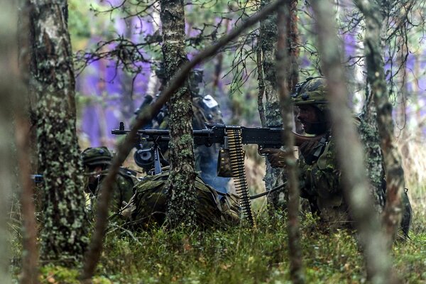 Soldato nascosto dietro gli alberi con le armi