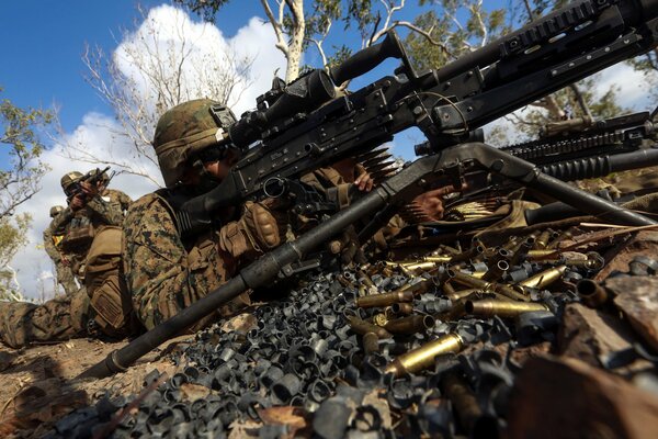 Ein Soldat, der liegend aus einem Maschinengewehr zielt