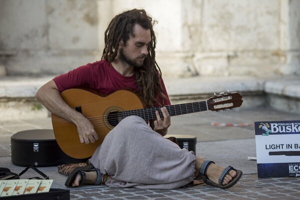 A street musician plays the guitar