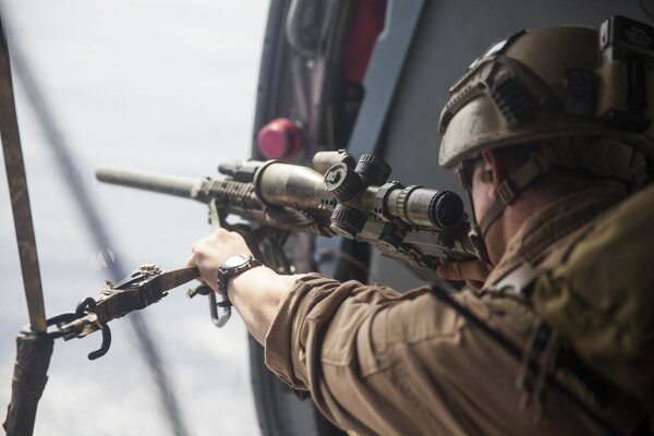 A soldier in a helmet with a sniper rifle in his hands