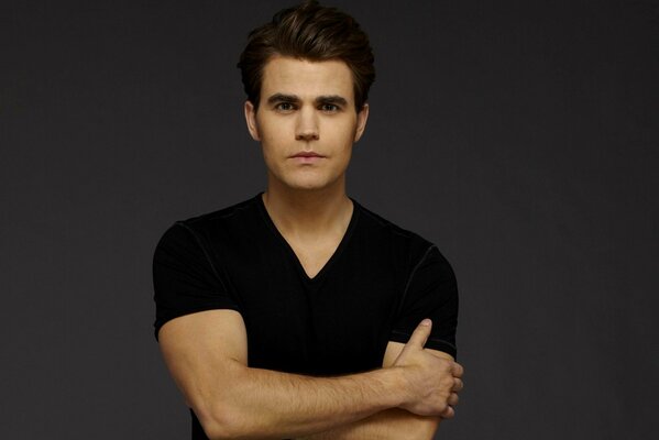 Actor Paul Wesley stands on a gray background