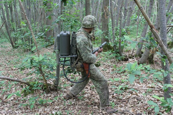 Mann in einer Kleidung, im Wald mit einem Flammenwerfer