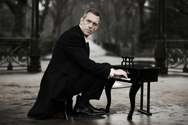 Hugh Laurie en train de jouer du piano dans le parc