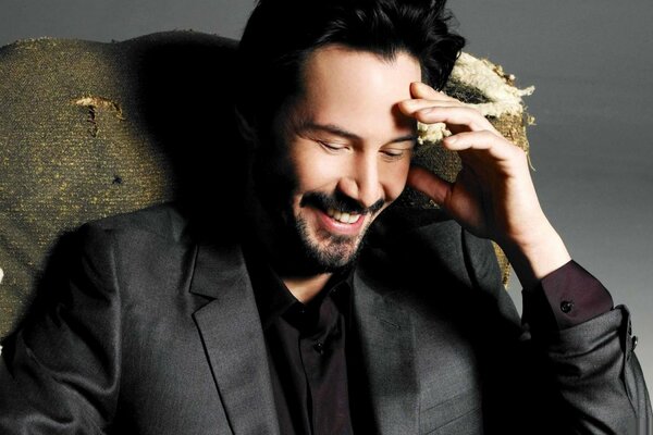 Keanu Reeves in a suit in a chair