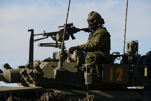 A soldier on a tank near a machine gun