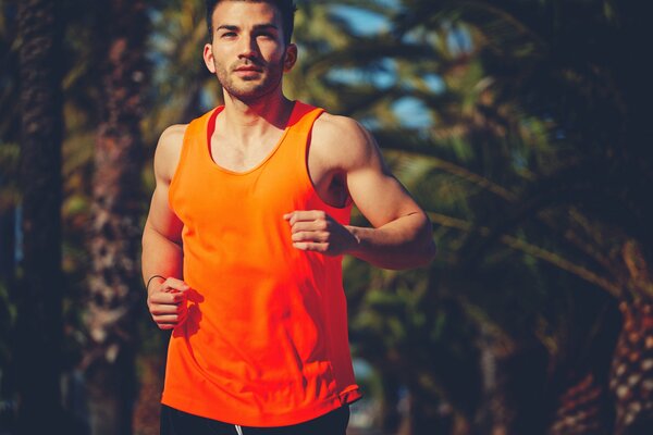 Ein Mann im orangefarbenen T-Shirt läuft durch den Park