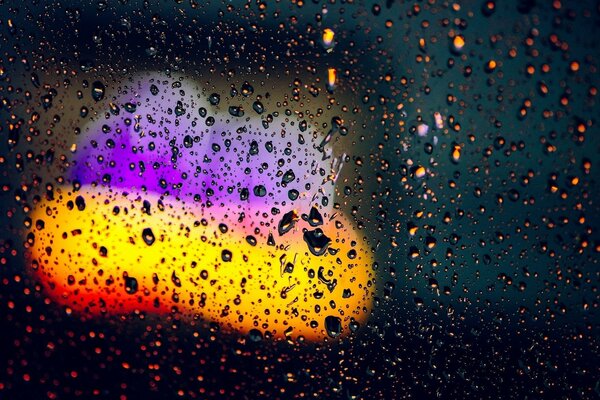 Raindrops on glass with yellow and purple lights