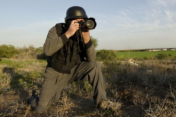 Foto de un corresponsal de guerra con una cámara en el campo