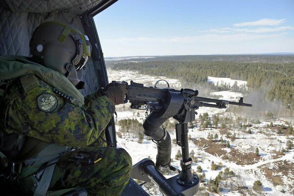 Un soldado con una ametralladora en un avión sobre el bosque