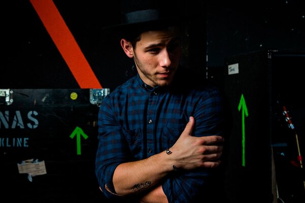 Nick Jonas hugs himself and looks to the left