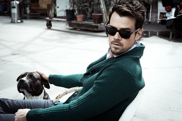 Actor Josh Duhamel in black glasses, green noodle sweater, stroking a dog