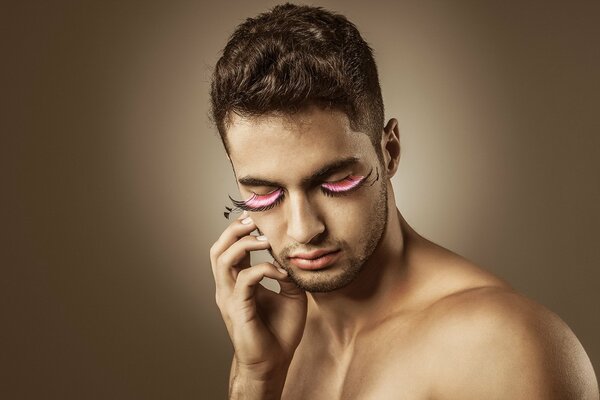 Beau mec posant sur fond avec des cils