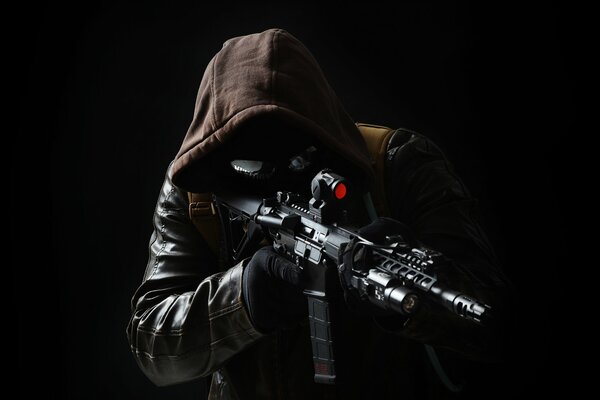 A hooded man with a gun in his hands