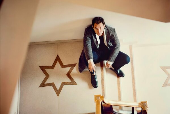 A man in a suit is sitting on the floor and posing