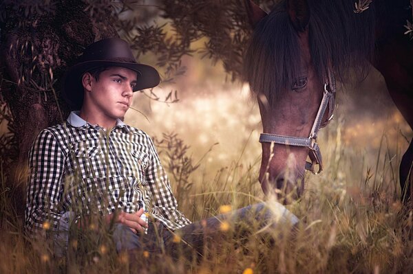 A young man walks in a field with a horse