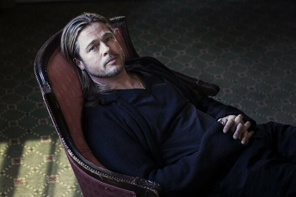 Brad Pitt with sad eyes is resting in a chair