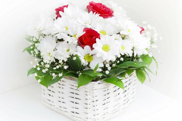 Bouquet de marguerites blanches et roses rouges dans un panier