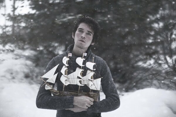 En el fondo de la nieve hay un chico con un barco OM en sus manos