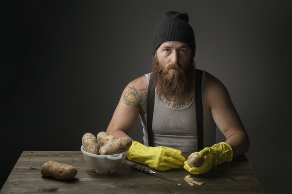 A man in a hat cleans a kortoshka with a knife