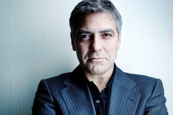 Джордж Клуни в пиджаке с ухмылкой и взглядом