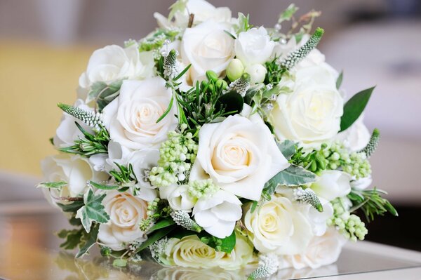 White bouquet of roses and green leaves on a mirror surface