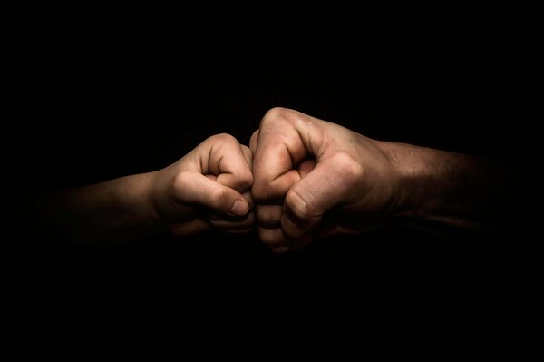 The image of the fists of a boy and a man together
