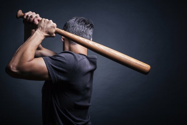A man with his back turned with a bat on the edge