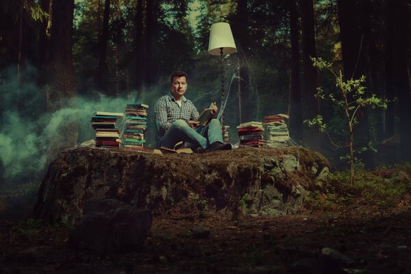 L homme du livre est assis au milieu de la forêt avec des livres et une lampe