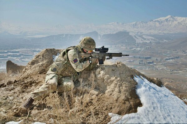 A shooter with a gun sitting in the mountains