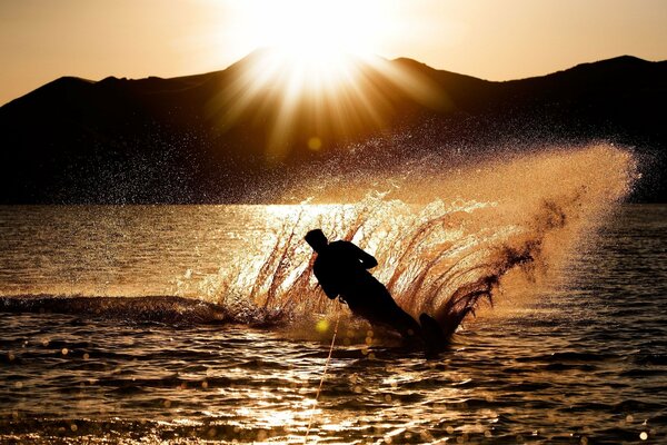 A man is engaged in water skiing at sunset