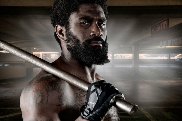 A bearded fighter in gloves holding an iron pipe