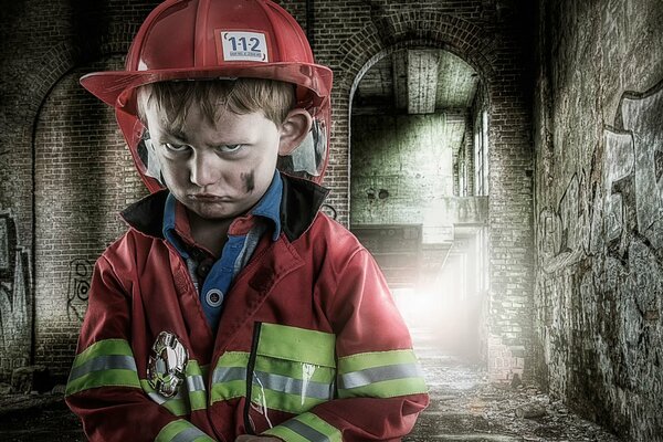 Piccolo ragazzo triste in uniforme antincendio