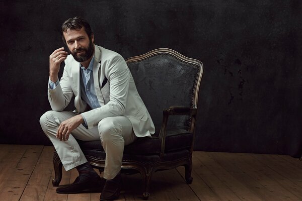 James Purefoy in a white suit sitting in a chair