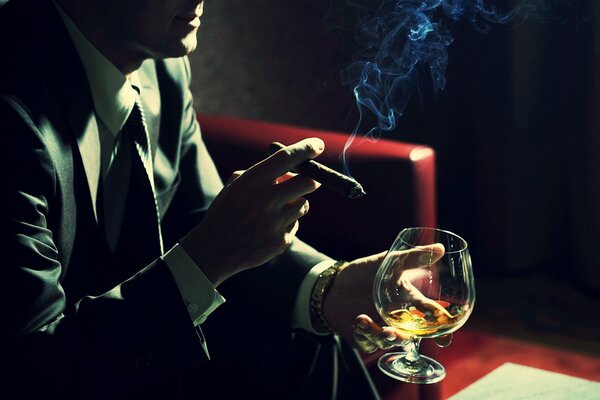 A man with a cigar and a glass of cognac