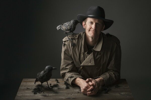 Homme au chapeau avec un corbeau sur l épaule