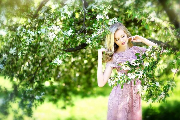 Dziewczyna w różowej sukience obok kwitnącego drzewa