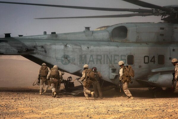 Soldiers in the desert near a large helicopter