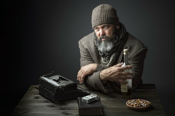 Escritor en la mesa con una botella y cigarrillos